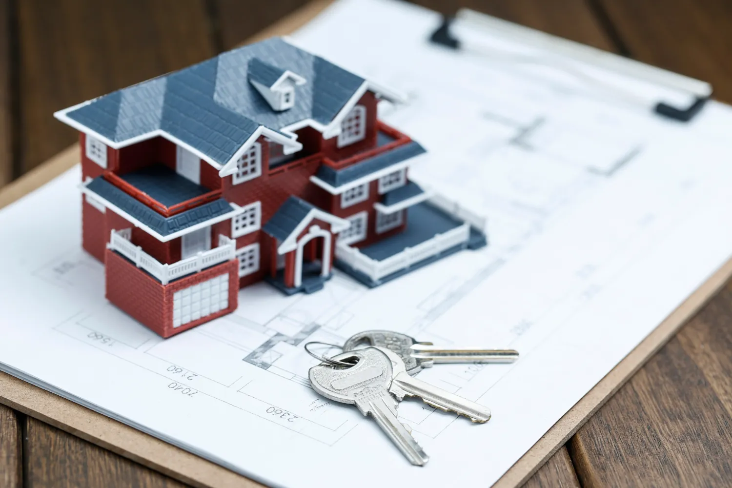 A model of a house and keys on top of a plan.